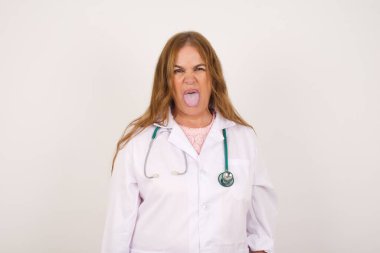 Vücut dili. Tıbbi üniforma giyen, suratını asan, bir şeyden tiksindiğini gösteren yetişkin, beyaz bir doktor kadın..