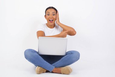 Pozitif sevinçli dişi der ki: Vay be, ne kadar heyecan verici, hayret verici bir ifade, bir şey ifade ediyor. Dizüstü bilgisayarı olan neşeli, güzel bir Arap kadın bir şey gösteriyor. Bir eli başının üstünde ve diğer eliyle işaret ediyor..