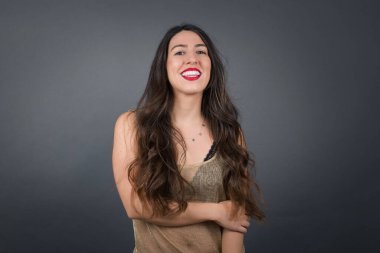 Gülümseyen güzel bir kadın. Gri arkaplanda duruyor. 