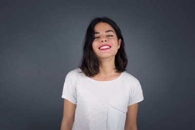 Hoş görünümlü beyaz bir kadının yatay portresi. Uzun, güzel saçlı, kahverengi kazak giyen, yüzünü saçlarıyla örten ve kameraya mutlu bir şekilde bakan..