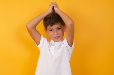 Sarı duvara yaslanmış sevimli çocuk.  