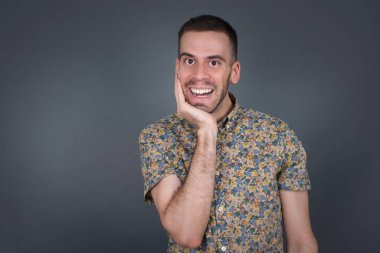 Şaşırtıcı derecede yakışıklı bir adam. Yakından bakınca insan portresi şaşırmış gibi görünüyor ağzı açık ve eli yüzün yanında. Olumlu duygu yüz ifadesi vücut dili. Komik çocuk.