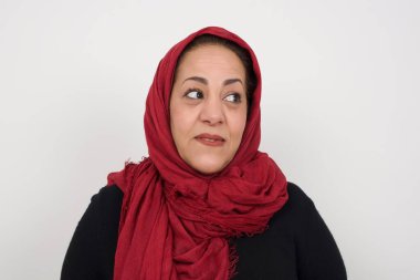 Hayalperest Müslüman kadın, düşünceli bir yüz ifadesi var, ellerini kaldırmıyor, dudaklarını ısırıyor, gri duvara karşı hoş bir poz düşünüyor..