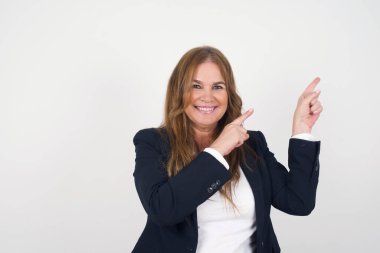 Reklam konsepti. Pozitif, güzel, orta yaşlı, gri arka planda kot gömlekli, ışıl ışıl gülümseyen kadın işaret parmağıyla işaret ediyor ve boş fotokopi odasına bakıyor..