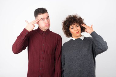 Genç çift izole edilmiş arka planda elleri silahlı jestler yapıyor.