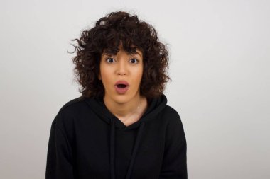 Çekici genç bir kadın ağzı açık, ağzı açık, ağzı açık bir şekilde şoke olmuş bir şekilde arkadaşının hikayesini dinlerken 