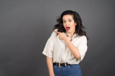 Gri arka planda gelişigüzel giyinmiş güzel esmer kadın..  