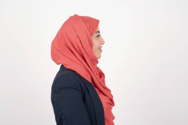 Güzel Müslüman kadının profili siyah ceket giyiyor ve tesettür beyaz stüdyo duvarına izole edilmiş.