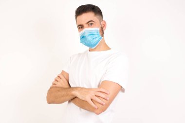 Yakışıklı, kendine güvenen, neşeli, genç girişimci, geniş bir gülümsemesi var, kollarını kavuşturuyor, şık giyinmiş meslektaşlarıyla tanıştığına seviniyor. Tıbbi maske takan beyaz bir adam.