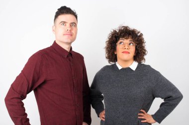 Neşeli, genç bir çiftin yukarı bakıp bir şeyler düşündükleri belden yukarı pozlar. Eller kalçada, yüz ifadesi şüpheli.. 