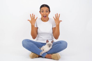 İnsanlar, başarı, galibiyet, zafer, heyecan, hedefler, kararlılık ve başarı konsepti. Neşeli, heyecanlı, şanslı öğrenci kadın tezahürat yapıyor, başarıyı kutluyor, yumruklarını sıkarak evet diye bağırıyor. Şirin kedisi olan güzel bir Arap kadın. 