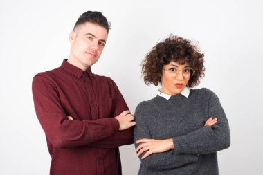 Güzel, genç bir çiftin belinde geniş bir gülümseme, kolları çapraz.