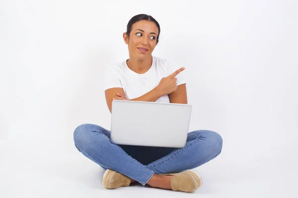 漂亮的黑发女人在镜头前摆出一副狡猾的样子 摆出一副侧身的姿势 女设计师用食指展示可爱的产品 Gesture概念 年轻美丽的阿拉伯妇女使用笔记本电脑 — 图库照片