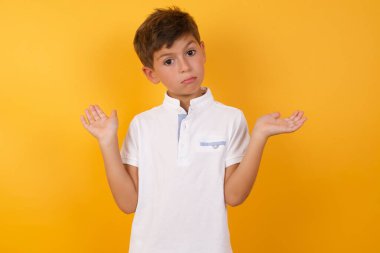 Sarı duvara yaslanmış kafası karışık şirin bir çocuk.  