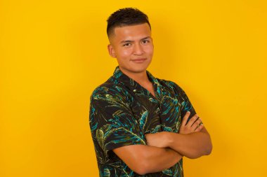 Genç yakışıklı adamın portresi mutlu gülümsüyor ve kollarını kavuşturup kameraya bakıyor. Pozitif ve kendinden emin kişi.