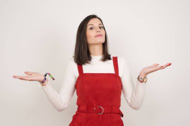 Kafası karışmış, kolları açık genç bir kadın omuzlarını silkip 