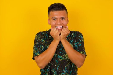 Stüdyodaki mutlu insan görüntüsü çene altında el ele tutuşur, keyifli bir ruh hali içindedir, ertesi gün için arkadaş fikrini sever, sarı duvarda izole edilmiş..