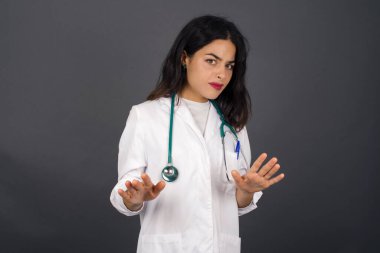 Tecrit edilmiş güzel bir doktor korkudan dehşete düşmüş ve tiksindirici bir ifade iki elinle hareket etmeyi kes ve orada kal. Panik konsepti.