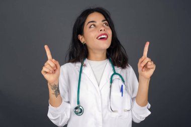 Başarılı, dost canlısı görünümlü, parlak makyajlı genç bir doktorun işaret parmağıyla işaret ederek boş bir fotokopi duvarında şok edici bir şey gösterdiği yatay görüntüsü..