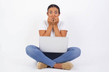 Anksiyete - dizüstü bilgisayarı olan güzel bir kadının kavramsal görüntüsü. Ağzını elleriyle kapatıyor ve dışarıda duruyor. Bir şeyden ya da birinin çivi yemesinden korktun mu?.