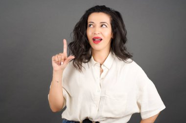 Gayri resmi giyinmiş güzel esmer kadın. Gri arkaplanda duruyor. 