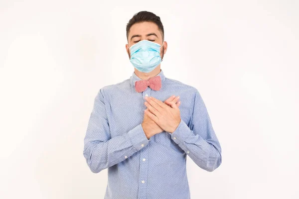 Trogen Man Bär Medicinsk Mask Blundar Och Håller Händerna Bröstet — Stockfoto