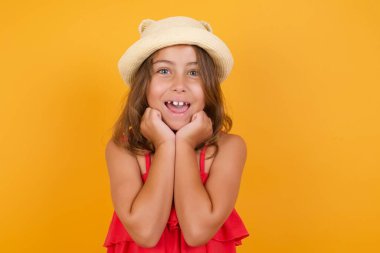 Sarı arka planda poz veren kırmızı elbiseli tatlı küçük kız. 