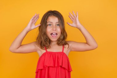 Sarı arka planda kırmızı elbiseler giyen tatlı küçük kız. 