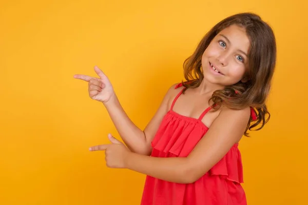 Cute Little Girl Noszenie Czerwonej Sukienki Wskazując Żółtym Tle — Zdjęcie stockowe