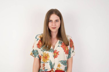 Stüdyoda, kıvırcık saçlı, sevimli bir gülümsemeyle kameraya bakan ve içeriğiniz için gri boş fotokopi duvarına poz veren güzel, genç, melez kadın modelin yakın çekimini yapın.