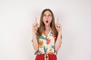 Güzel, zarif bir kadının portresi izole edilmiş arka planda şaşkın şaşkın bakıyor ve parmaklarıyla garip bir şey gösteriyor..