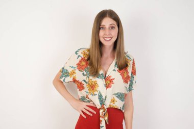 Neşeli iş kadınının stüdyo çekimi elini kalçasında tutuyor, geniş bir şekilde gülümsüyor, arkadaşlarının doğum gününde hazırladığı sürprizi bekliyor, gri arka planda izole edilmiş..