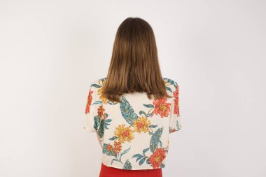 Gri duvarda duran uzun dalgalı ve parlak saçlı bir kızın arka tarafı. Stüdyo Çekimi. 