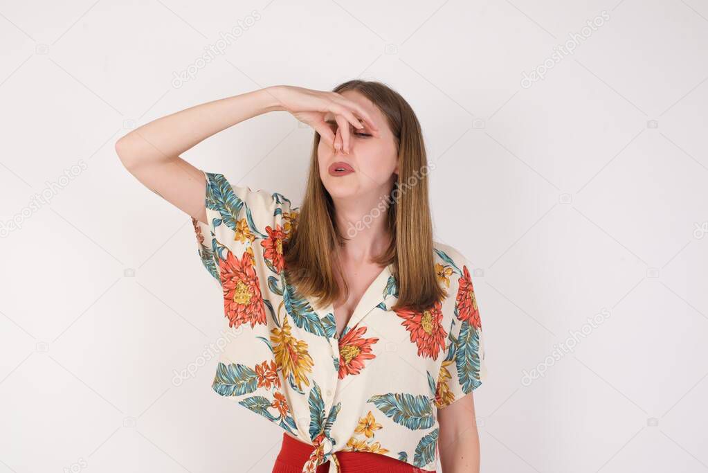 Displeased brunette female isolated over grey background plugs nose as smells something stink and unpleasant, feels aversion. Young attractive woman hates disgusting scent which comes from next room