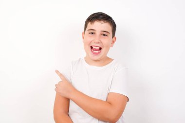 Yakışıklı esmer beyaz çocuk, beyaz arka planda dururken seni işaret ediyor ve gülümsüyor..