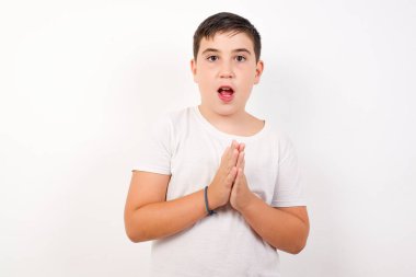 Beyaz duvara karşı duran başarılı beyaz çocuk, mutlu hissediyor, el çırpıyor, alkışlarla tebrik ediyor..