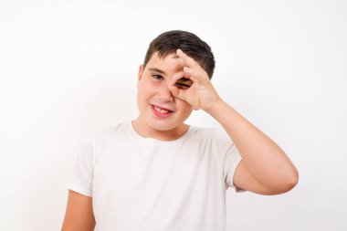 Gülümseyen güzel beyaz çocuk el pençe divan, el pençe divan bakıyor. Günlük giysiler giyip stüdyoda dikiliyor.