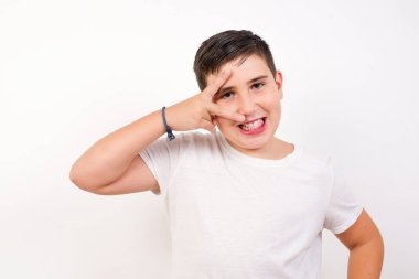 İnsanların flört konseptini kutladıkları boş bir yaşam tarzı. Yakışıklı, neşeli, açık havada dikilen günlük giysiler giymiş, gözlerinin yanında V işareti yapan bir çocuk..