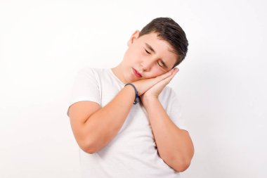 Gözleri kapalı, yorgun, yastık gibi avuçlarına yaslanmış, yorgun düşmüş gibi yapan, arka planda duran rüyalar gören, yorgun ve yakışıklı bir çocuk. Uyuma hareketi.