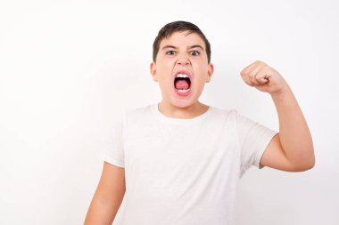 Sert, kendine güvenen, koyu renk saçlı bir çocuk. Önünde yumruğunu tutuyor. Sanki dövüşe ya da meydan okumaya hazır gibi. Beyaz arkaplan üzerinde izole edilmiş.