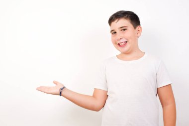 Olumlu sevinçli çocuk, boş bir alanda, izole edilmiş beyaz arka planı olan bir şey gösteriyor. Reklam kavramı.