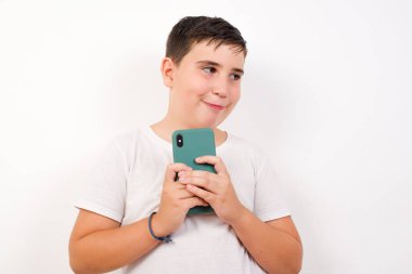 Yakışıklı bir gencin portresi, hayalperest bakışlı, akıllı telefonu tutarken düşünen, beyaz arka planda izole edilmiş..