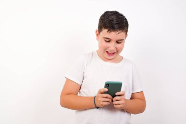 Yakışıklı, gülümseyen, cep telefonu kullanan, mesajlaşan, kız arkadaşıyla mesajlaşmaktan mutlu olan, akıllı telefona bakan bir çocuk. Modern teknolojiler ve iletişim.