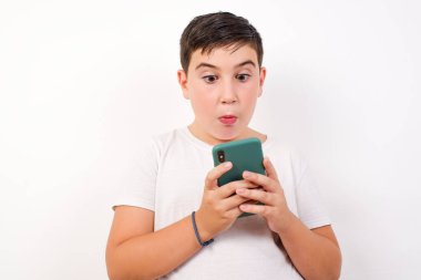 Yakışıklı bir gencin yatay görüntüsü, beyaz arka planda izole edilmiş, böcek gözlü, modern akıllı telefonu olan, arkadaşından beklenmedik bir mesaj alan,.