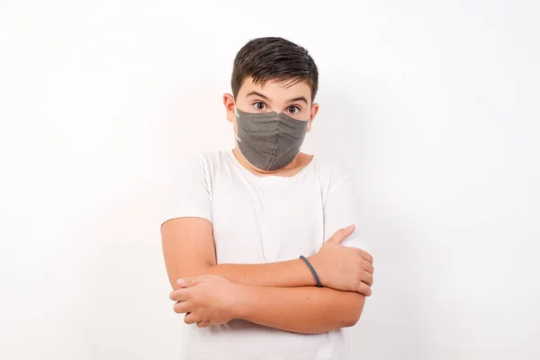 Isolated portrait of stylish young European boy bitting his mouth and looking worried and scared crossing arms, worry and doubt.