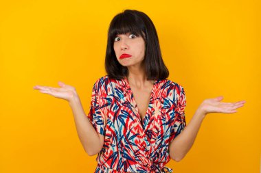 Kafası karışmış, kolları açık genç bir kadın omuzlarını silkip 