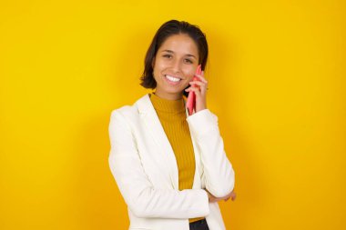 Gülümseyen, sıradan esmer bir kadının cep telefonuyla konuşan portresi. 