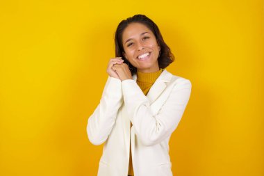 Hoş bir ifadeyle hayalperest genç bir kadın, gözlerini kapatıyor, ellerini yüzüne çarpıyor, hoş bir şey düşünüyor, arka planda poz veriyor..