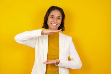 İzole edilmiş arka planda genç ve güzel bir kadın. Elleri büyük ve büyük bir işaret, ölçü sembolü gösteriyor. Kameraya bakıp gülümsüyor. Ölçüm konsepti. 