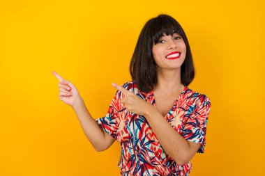 Reklam konsepti. Pozitif, güzel, ışıltılı gülüşü olan beyaz kadın, işaret parmağıyla işaret ediyor ve boş fotokopi odasına bakıyor..
